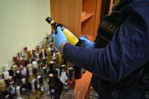 policjant prowadzi czynności w związku z zabezpieczonymi napojami alkoholowymi