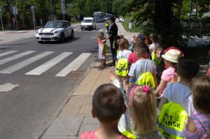 policjanci i dzieci ćwiczą właściwe przechodzenie przez przejście dla pieszych