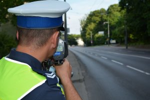 policjant mierzy prędkość pojazdów jadących ulicą