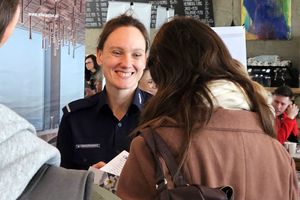 Na zdjęciu uśmiechnięta policjantka, która rozmawia z kobietą w stroju cywilnym