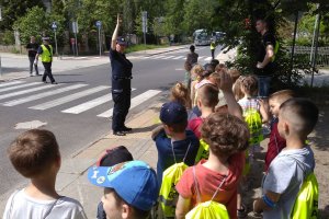 policjanci i dzieci ćwiczą właściwe przechodzenie przez przejście dla pieszych