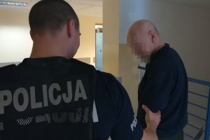 policjant prowadzi zatrzymanego