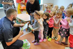 policjant rozdaje książki edukacyjne