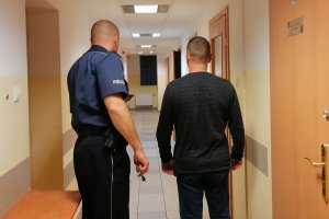 policjant prowadzi zatrzymanego