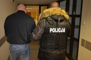 Policjant prowadzi zatrzymanego