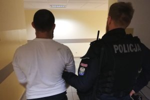 policjant prowadzi zatrzymanego