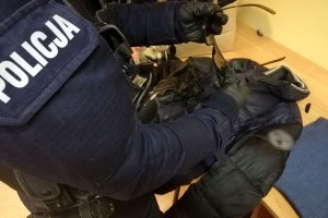 policjant dokonuje oględzin odzyskanych rzeczy