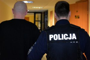 policjant prowadzi zatrzymanego