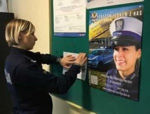 policjantka wywiesza plakat i ulotki