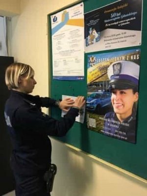 policjantka wywiesza plakat i ulotki