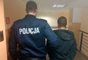 policjant prowadzi zatrzymanego