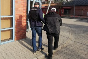 policjant prowadzi zatrzymanego