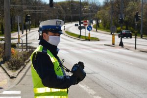 policjant ruchu drogowego w trakcie służby na ulicy, kontroluje prędkość pojazdów