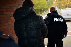 policjanci prowadzą zatrzymanego