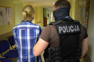 policjant prowadzi zatrzymaną kobietę