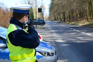 policjant mierzy prędkość jadącemu ulicą samochodowi