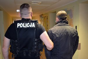 policjant prowadzi zatrzymanego mężczyznę