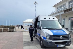 Na zdjęciu mobilny komisariat przy wejściu na molo. Przy radiowozie stoi umundurowana policjantka.