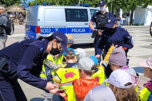 Umundurowani policjanci wręczają dzieciom odblaski