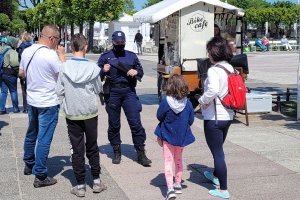 Deptak. Umundurowana policjantka rozmawia z osobami.