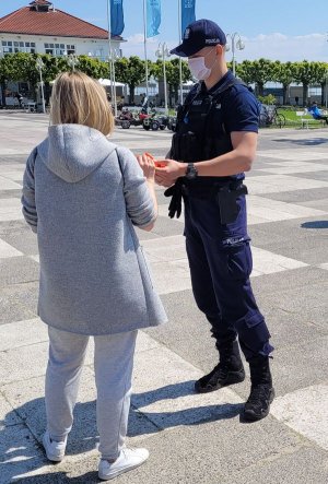 Umundurowany policjant rozmawia z kobietą.