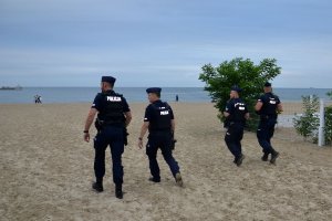 Umundurowani policjanci idą po plaży.