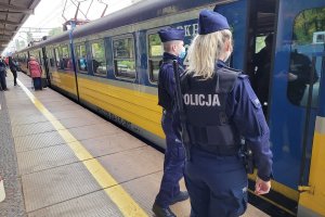 Umundurowani policjanci wchodzą do pociągu stojącego przy peronie