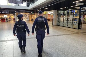 Umundurowani policjanci idą przez hol budynku. W tle widać inne osoby. Zdjęcie archiwalne.