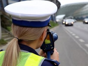 Umundurowana policjantka mierzy prędkość pojazdu jadącego ulicą. Zdjęcie poglądowe.