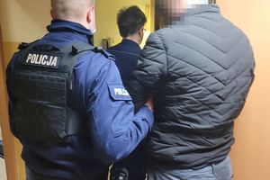 Umundurowani policjanci wprowadzają do pomieszczenia zatrzymanego mężczyznę