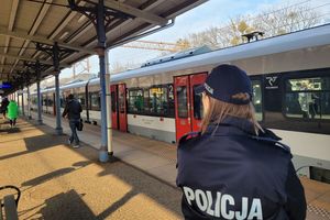 Peron dworca kolejowego. Umundurowana policjantka obserwuje osoby wysiadające z pociągu.