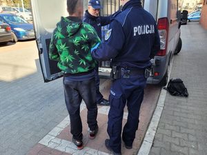 Umundurowani policjanci wprowadzają do radiowozu zatrzymanego mężczyznę