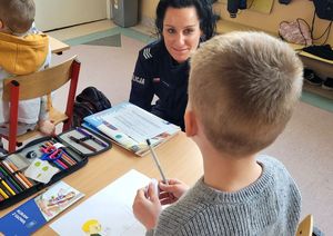 Klasa szkolna. Policjantka rozmawia z dzieckiem