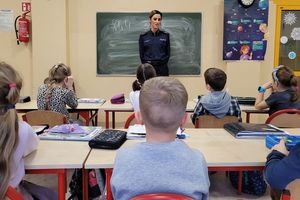 Klasa szkolna. Umundurowana policjantka rozmawia z dziećmi.