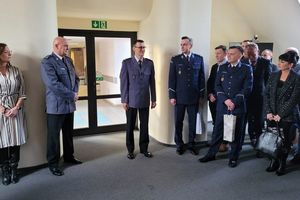 Pomieszczenie służbowe. Na zdjęciu umundurowani policjanci oraz mężczyźni i kobiety w strojach cywilnych.