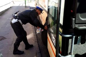 Pora dzienna. Umundurowany poilcjant ogląda koło autobusu. Zdjęcie archiwalne.