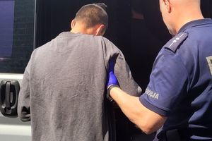 Umundurowany policjanty prowadzi mężczyznę w stroju cywilnym