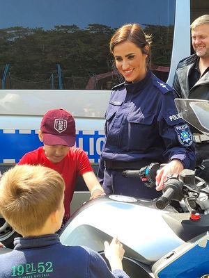Na zdjęciu stoisko policyjne, gdzie umundurowani policjanci pokazują dzieciom oznakowany motocykl