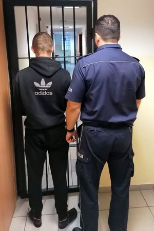 Policjant prowadzi zatrzymanego mężczyznę