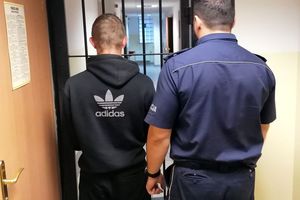 Policjant prowadzi zatrzymanego mężczyznę