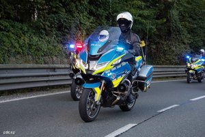 Trzech umundurowanych policjantów jedzie ulicą na motocyklach