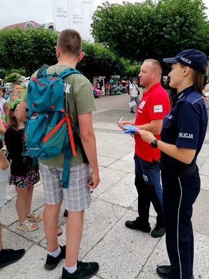 Na zdjęciu policjantka i ratownik wodny rozmawiający z grupą osób