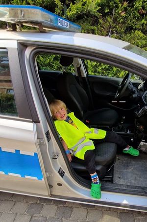 Na zdjęciu dziecko - mały chłopiec siedzący na fotelu pasażera w policyjnym radiowozie