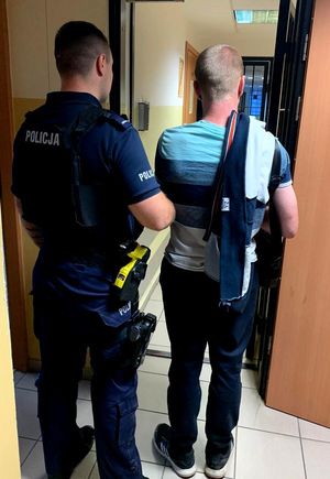 Policjant prowadzi zatrzymanego mężczyznę