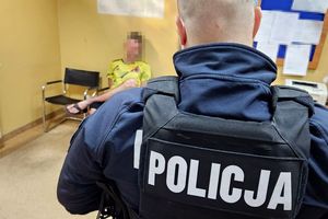 Na zdjęciu policjant, a za nim na krześle siedzi zatrzymany mężczyzna