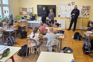 Na zdjęciu policjantka, policjant, nauczycielka i grupa dzieci.