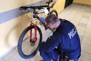 Na zdjęciu policjant, który ogląda rower. Zdjęcie archiwalne.