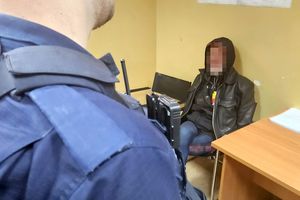 Na zdjęciu policjant oraz zatrzymany mężczyzna, który siedzi na krześle