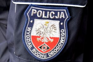 Na zdjęciu rękaw munduru, a na nim naszywka policyjna. Na naszywce znajdują się napisy: POLICJA i WYDZIAŁ RUCHU DROGOWEGO oraz na biało-czerwonym tle znajduje się godło Polski i logo policyjne w kształcie rombu z literą R na środku.