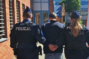 Na zdjęciu policjantka, policjant i zatrzymany mężczyzna, który ma kajdanki założone na ręce trzymane z tyłu